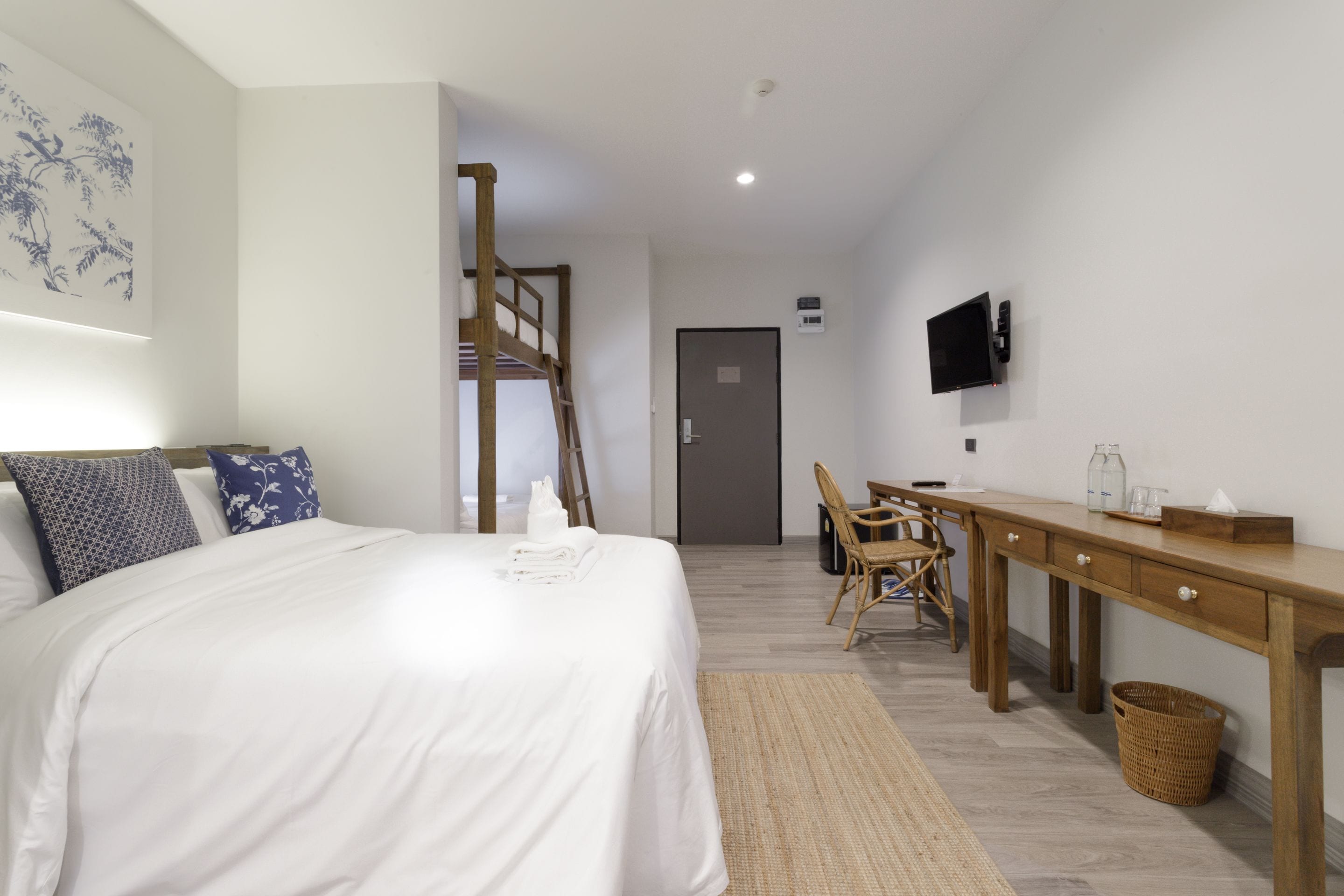 A bedroom with a bed, a desk, a chair, a TV, and a wooden ladder.