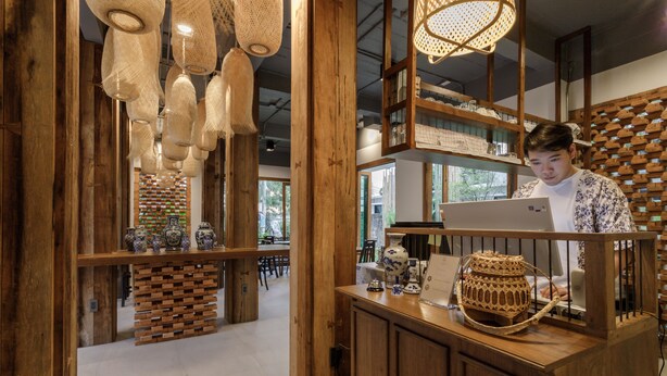 A wooden interior with a reception desk, hanging light fixtures, and shelves with decorative items. - The Locals Chiang Mai (Chiang Mai)
