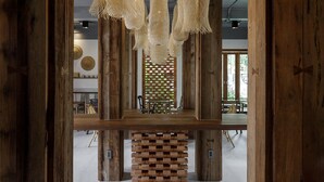 A wooden interior with hanging woven light fixtures, a brick wall, and a view of a dining area. - The Locals Chiang Mai (Chiang Mai)