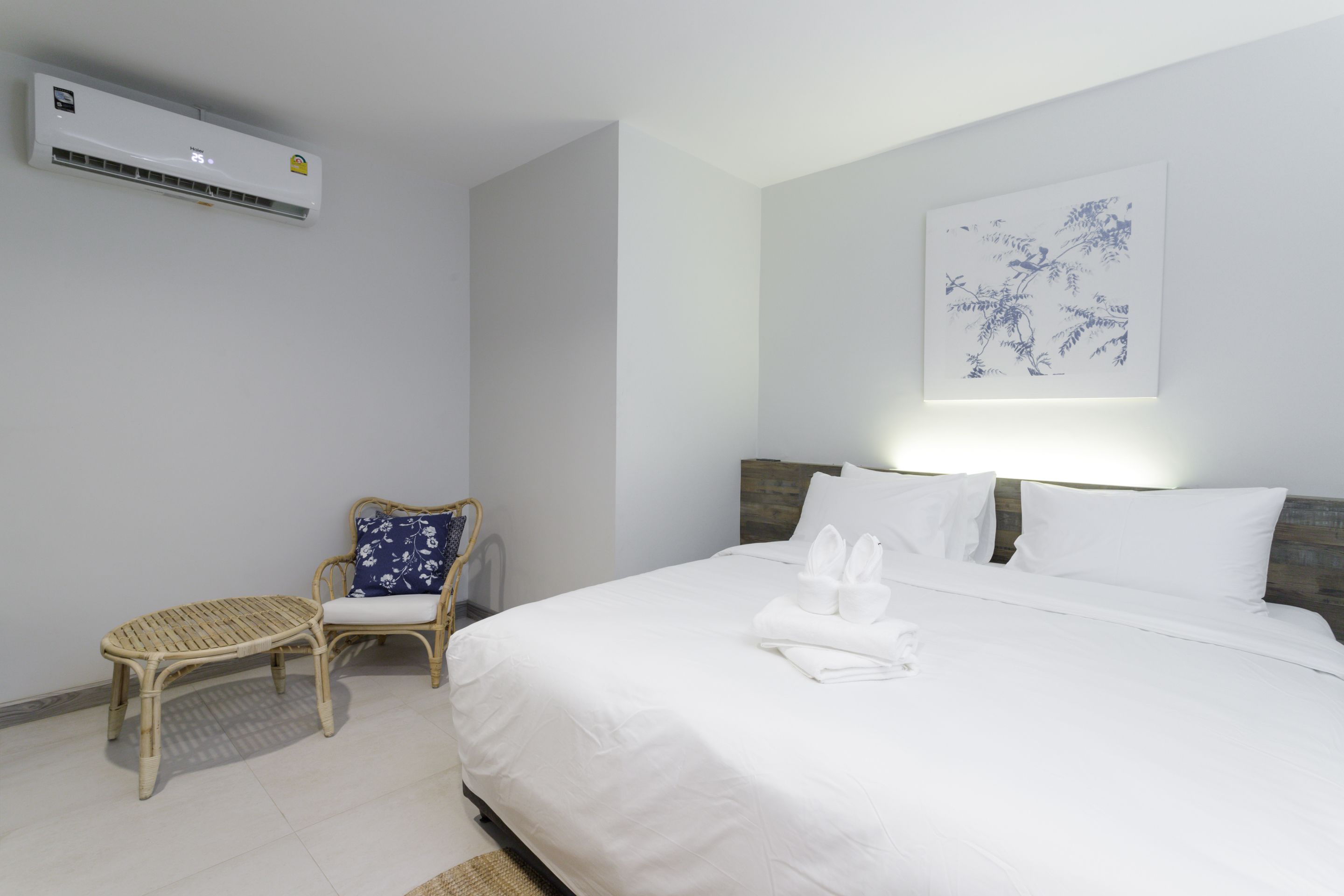 Una habitación de hotel con una cama, una silla, aire acondicionado instalado en la pared y una obra de arte en la pared.
