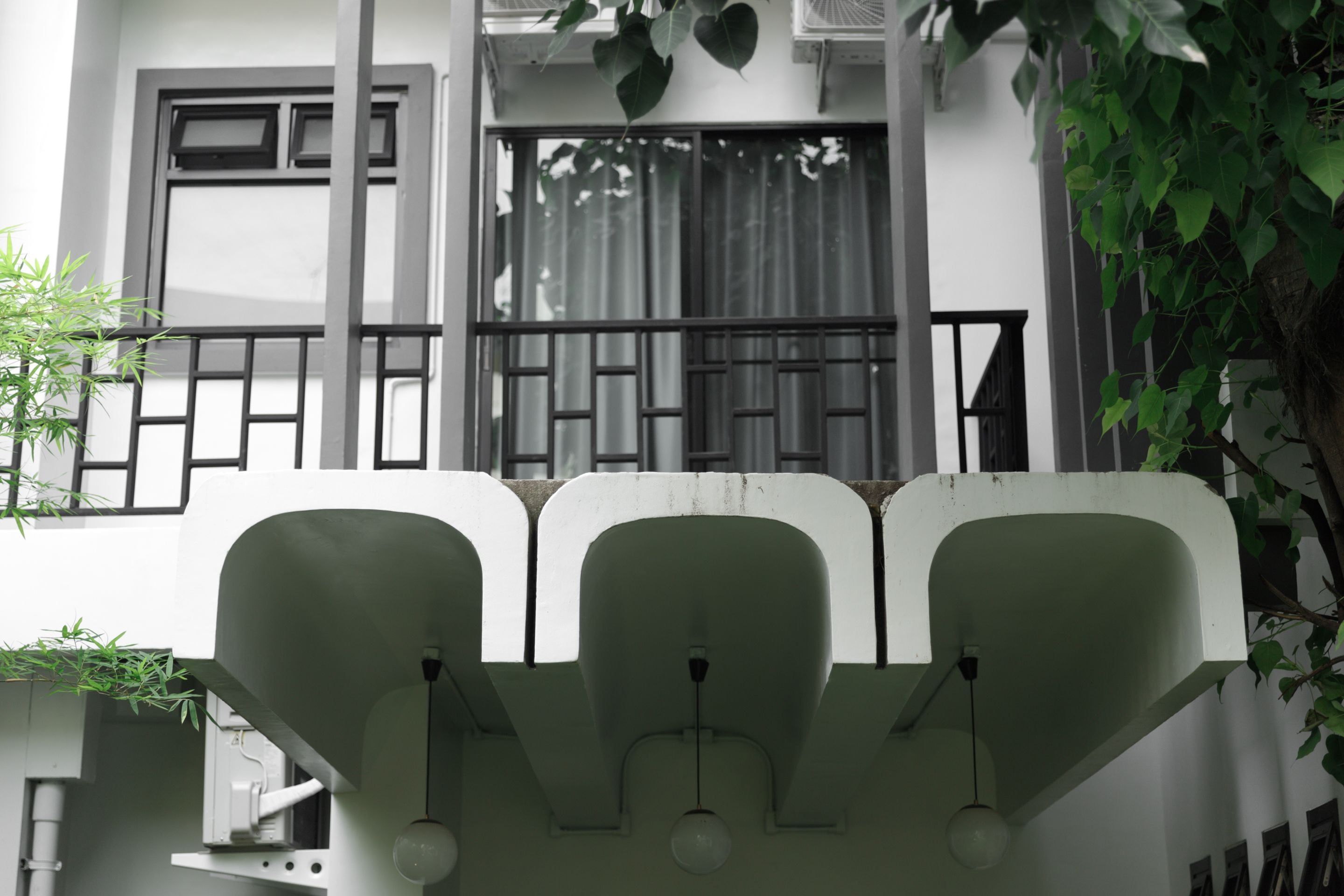 Een gevel met balkon, een raam met gordijnen en een hangplant.