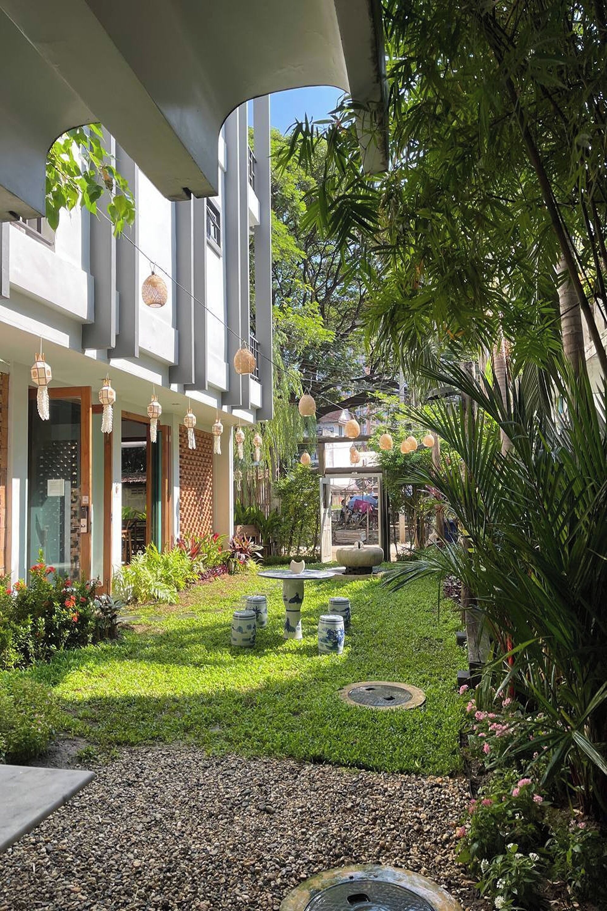 A modern building with a garden courtyard, outdoor seating, and hanging lanterns.