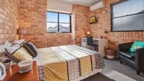 Una habitación con cama, escritorio, silla y ventana.