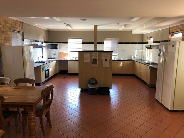 A kitchen with a dining table and chairs, a refrigerator, a microwave, and a sink. - Hanbury Lodge (Mayfield)