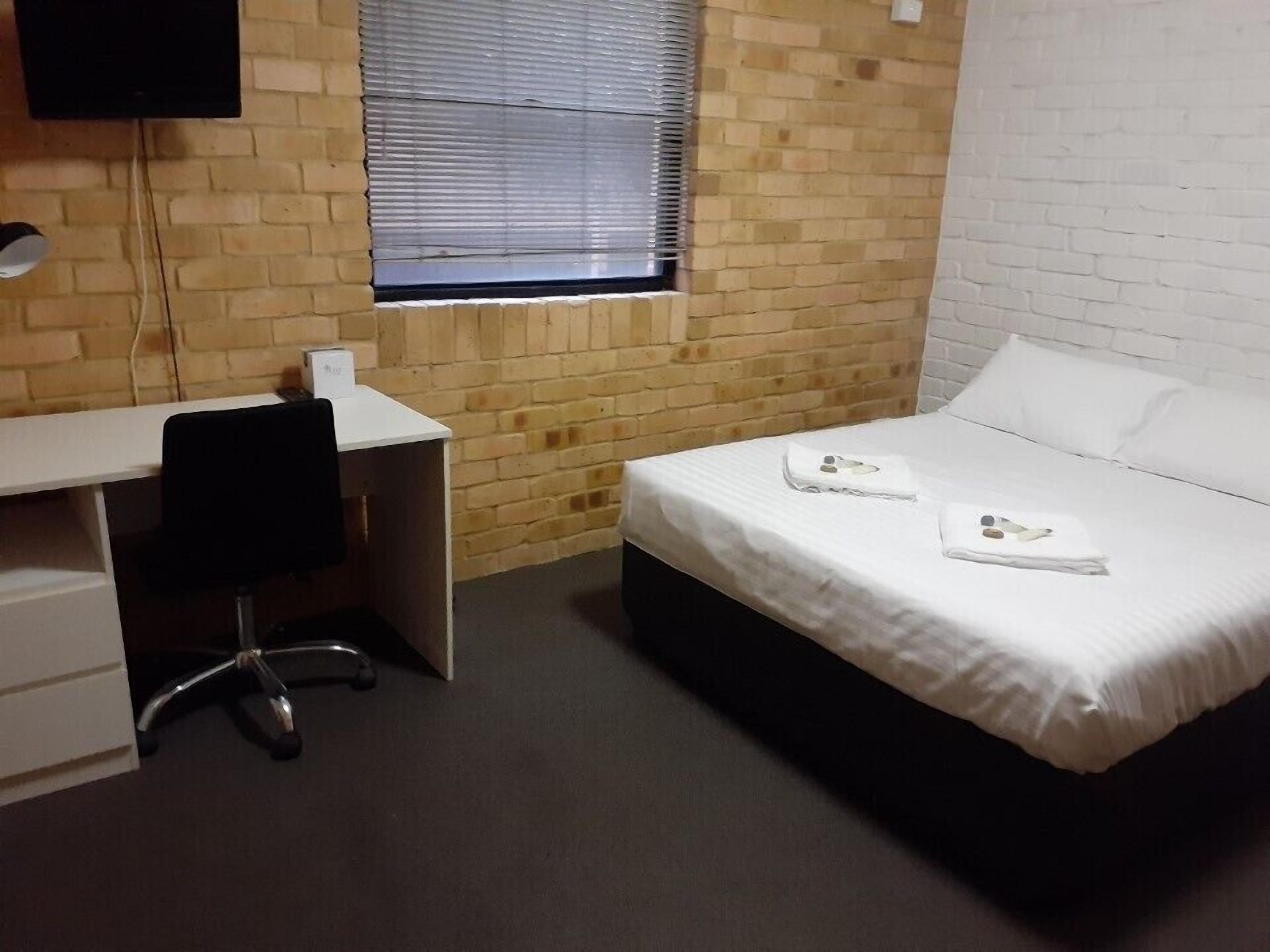 A small, clean room with a bed, a desk, and a chair.