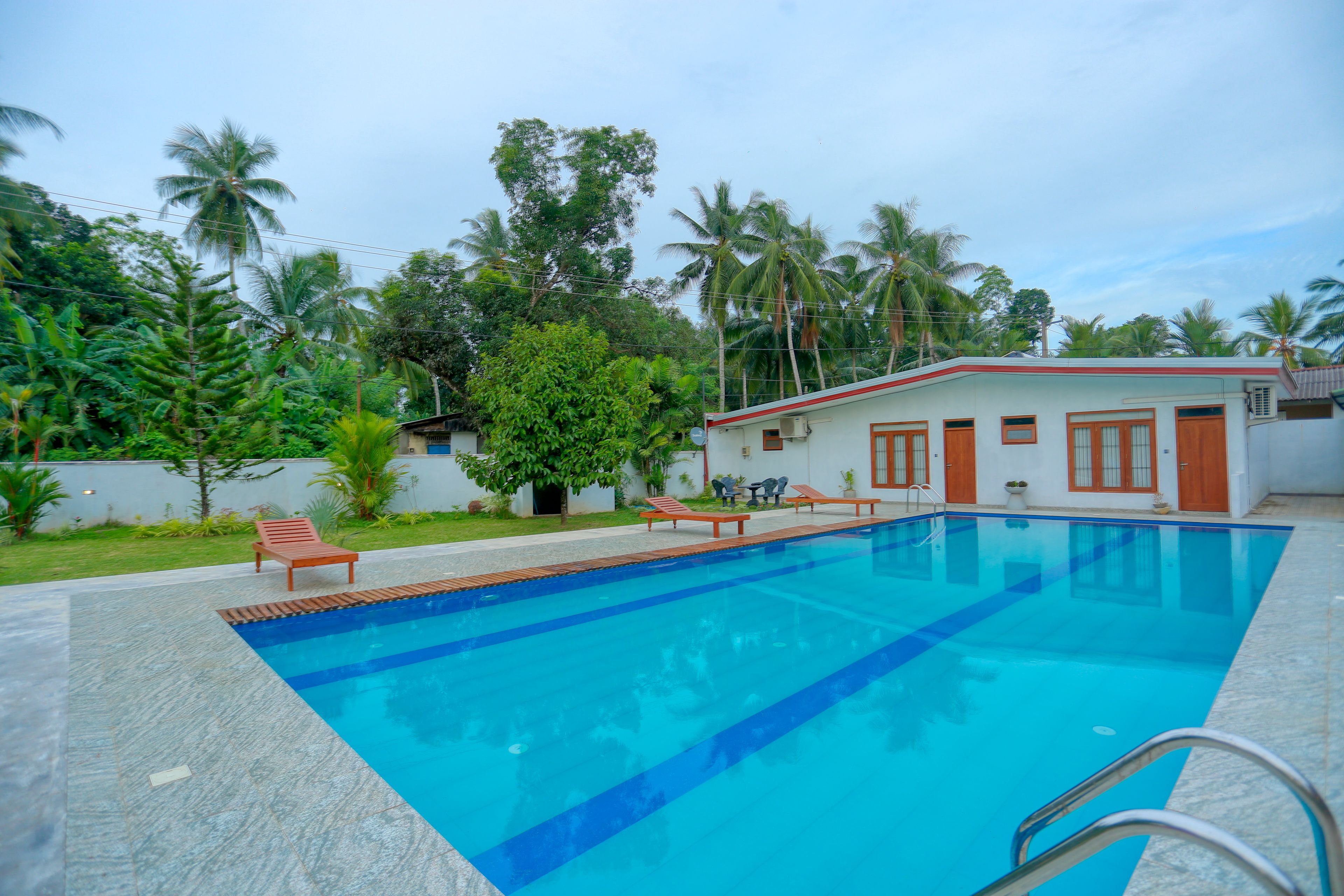 Piscina retangular com linha d'água azul cristalina, rodeada por um deck revestido de azulejos.