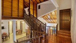 A spacious interior with a wooden staircase, a dining area, and a view of a pool. - Om Residence (Beruwela)