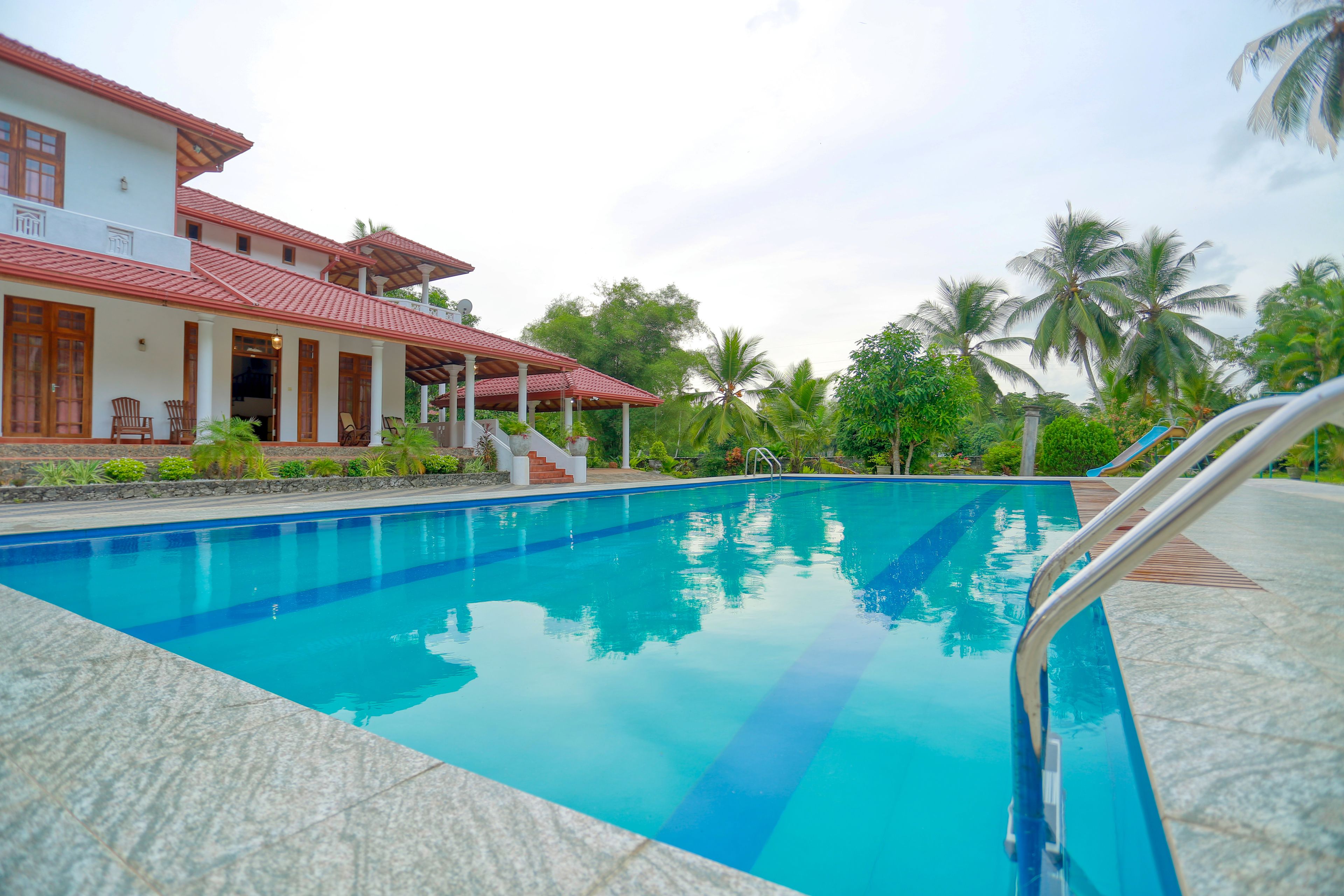 Una piscina con agua azul cristalina, rodeada por un solado de azulejos.
