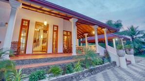 A two-story building with a covered porch, stone steps, and potted plants. - Om Residence (Beruwela)