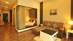 Een moderne hotelkamer met een groot bed, een slaapbank, een klein tafeltje en uitzicht op de stad door een glazen deur.