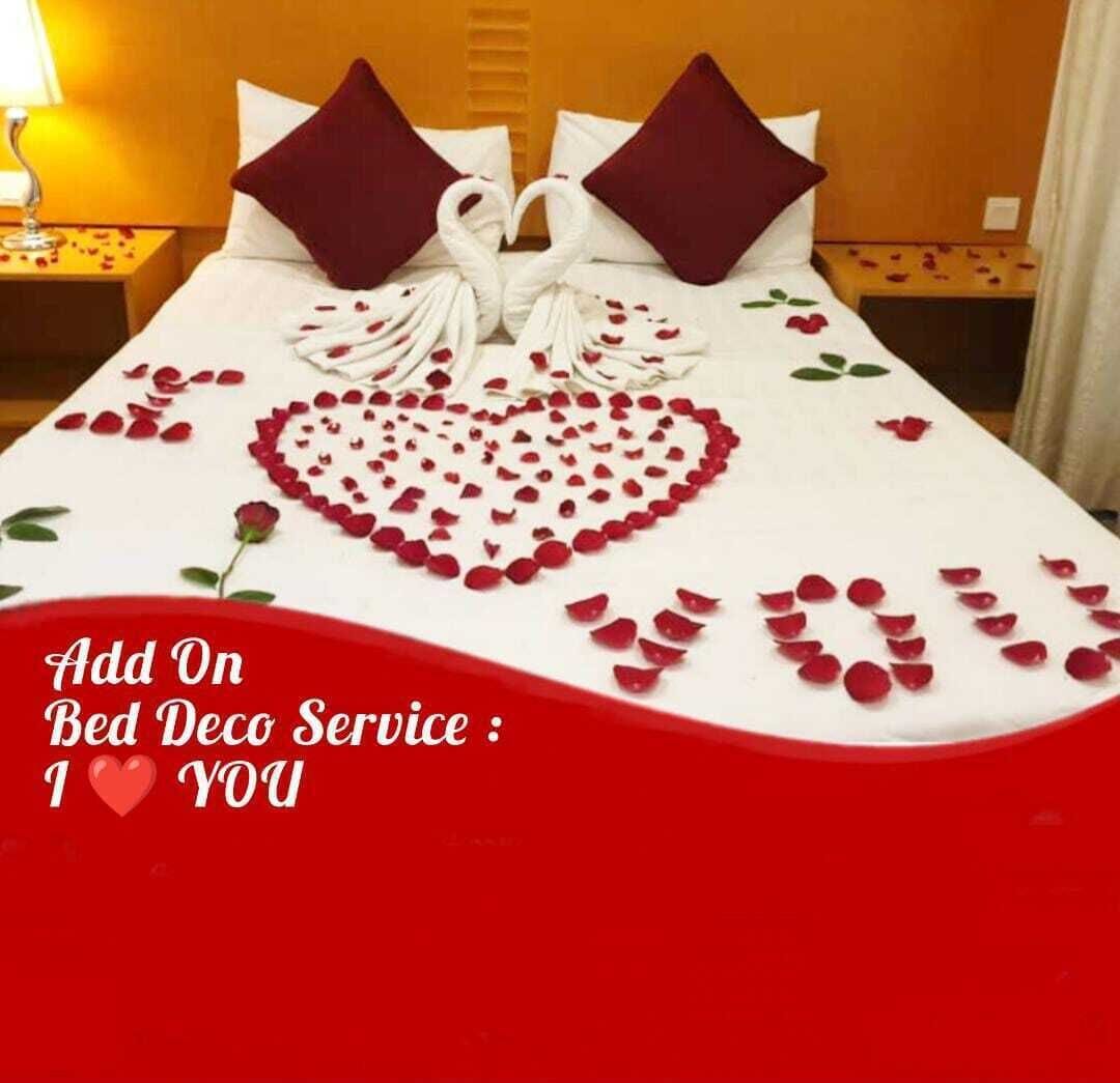 A bed with a heart-shaped arrangement of rose petals and a swan-shaped towel.