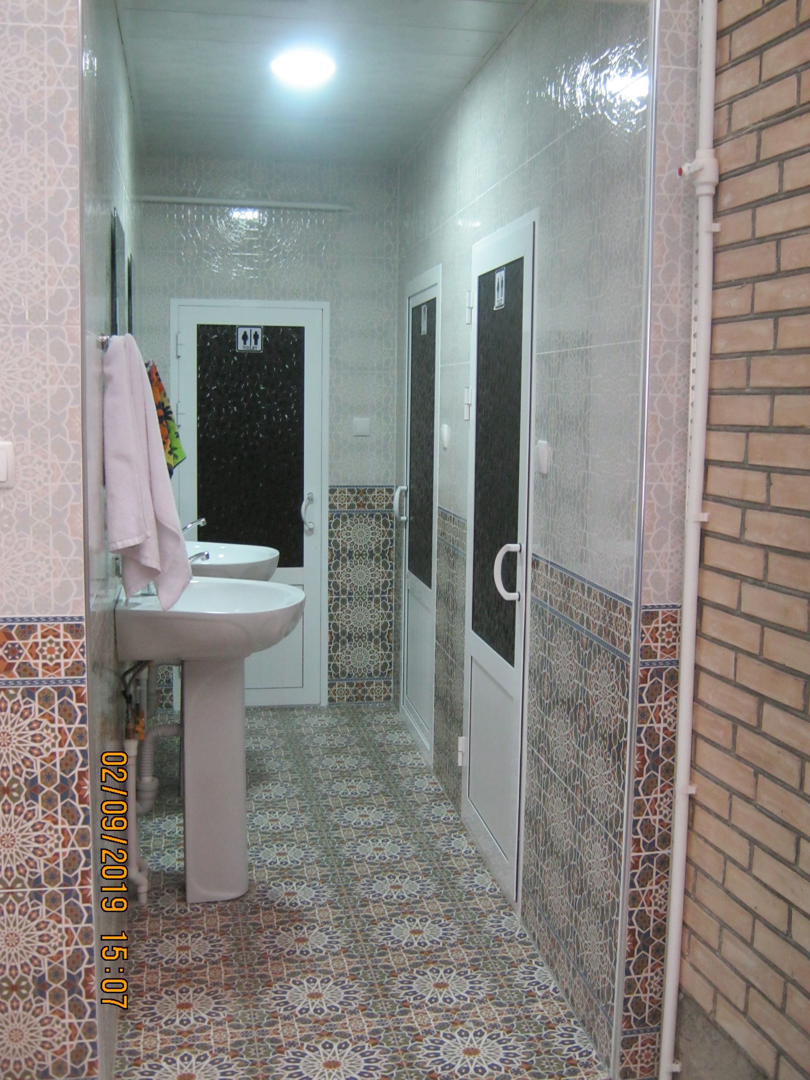 A narrow bathroom with a sink, a toilet, and a shower area.