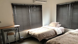 A bedroom with two beds, a desk, and a chair. - Yoko House (Uruma)