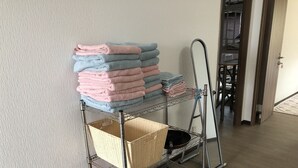 A metal shelf unit with folded towels and a wicker basket. - Yoko House (Uruma)