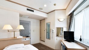 A hotel room with a bed, desk, TV, and a bathroom door. - Chino Sky View Hotel (Chino)