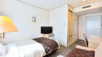 A hotel room with a bed, a television, a desk, and a door.