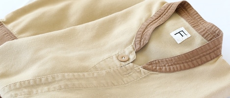 A folded beige shirt with a brown collar and a visible brand tag.