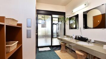 A modern bathroom with two sinks, a large mirror, and wicker baskets on shelves.