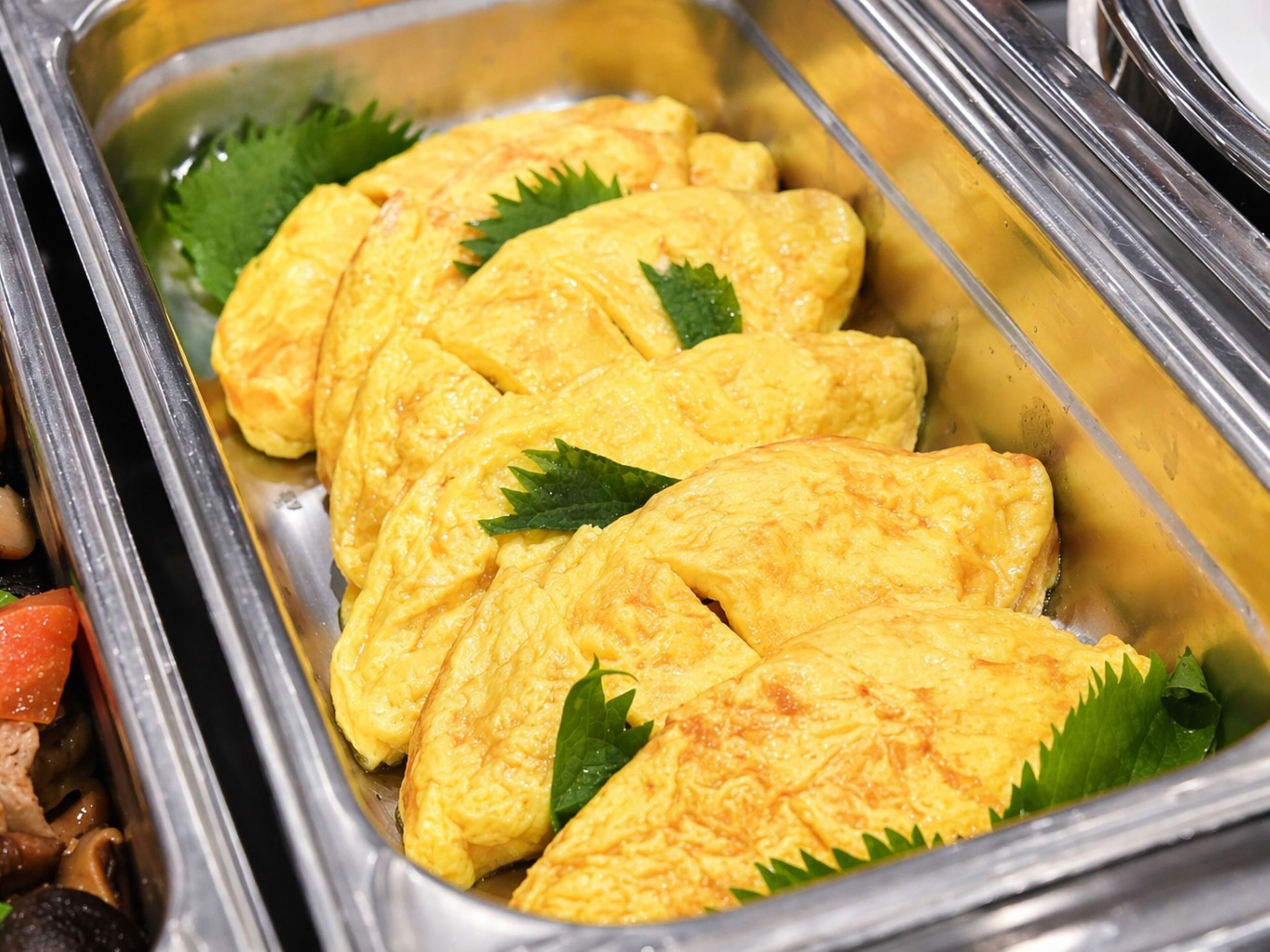 A buffet with sliced omelettes garnished with green leaves.