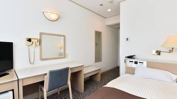 Une chambre d’hôtel équipée d’un lit, d’un bureau, d’une chaise, d’une télévision et d’un miroir.