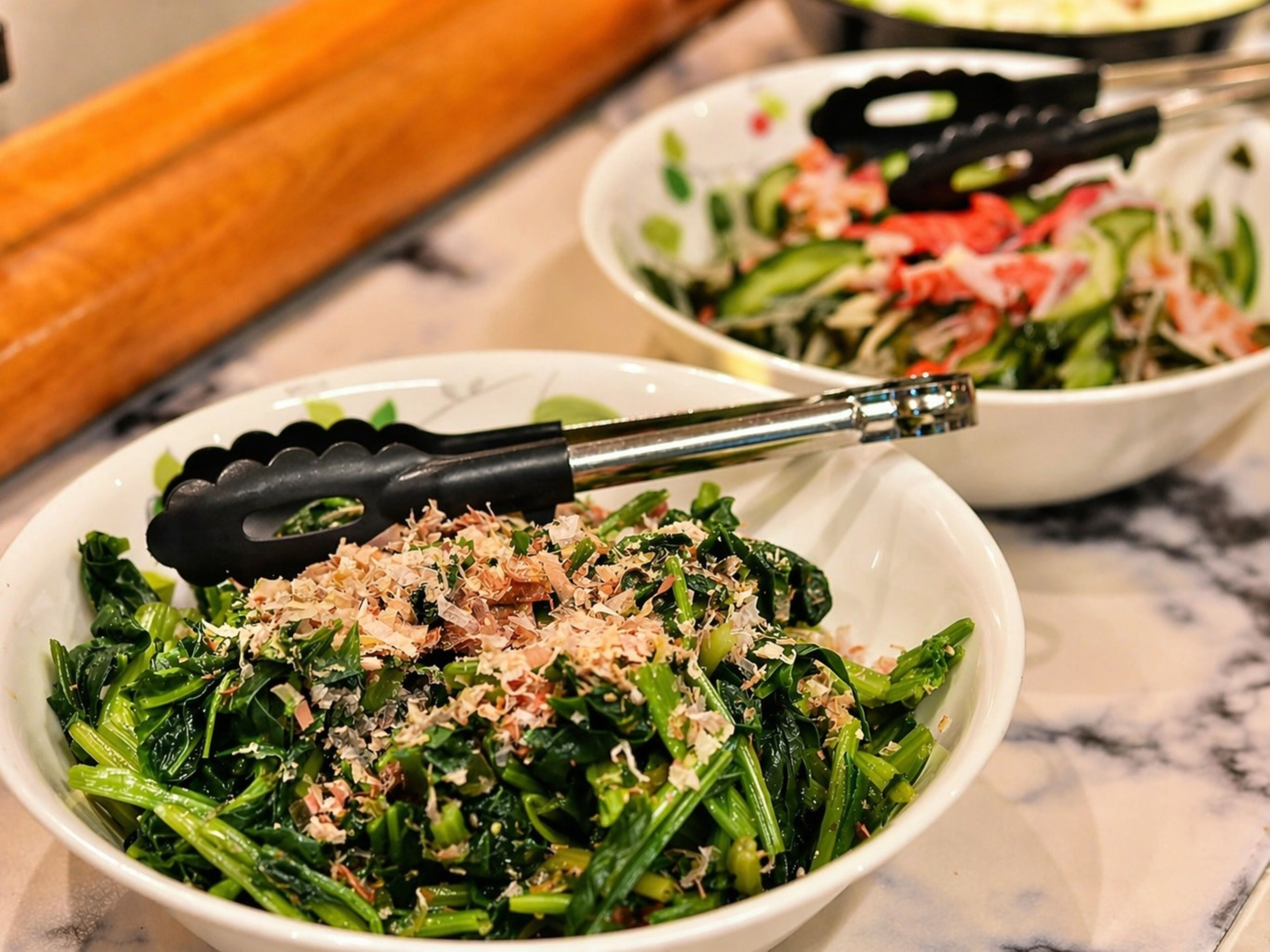 A bowl of cooked greens with a fork.