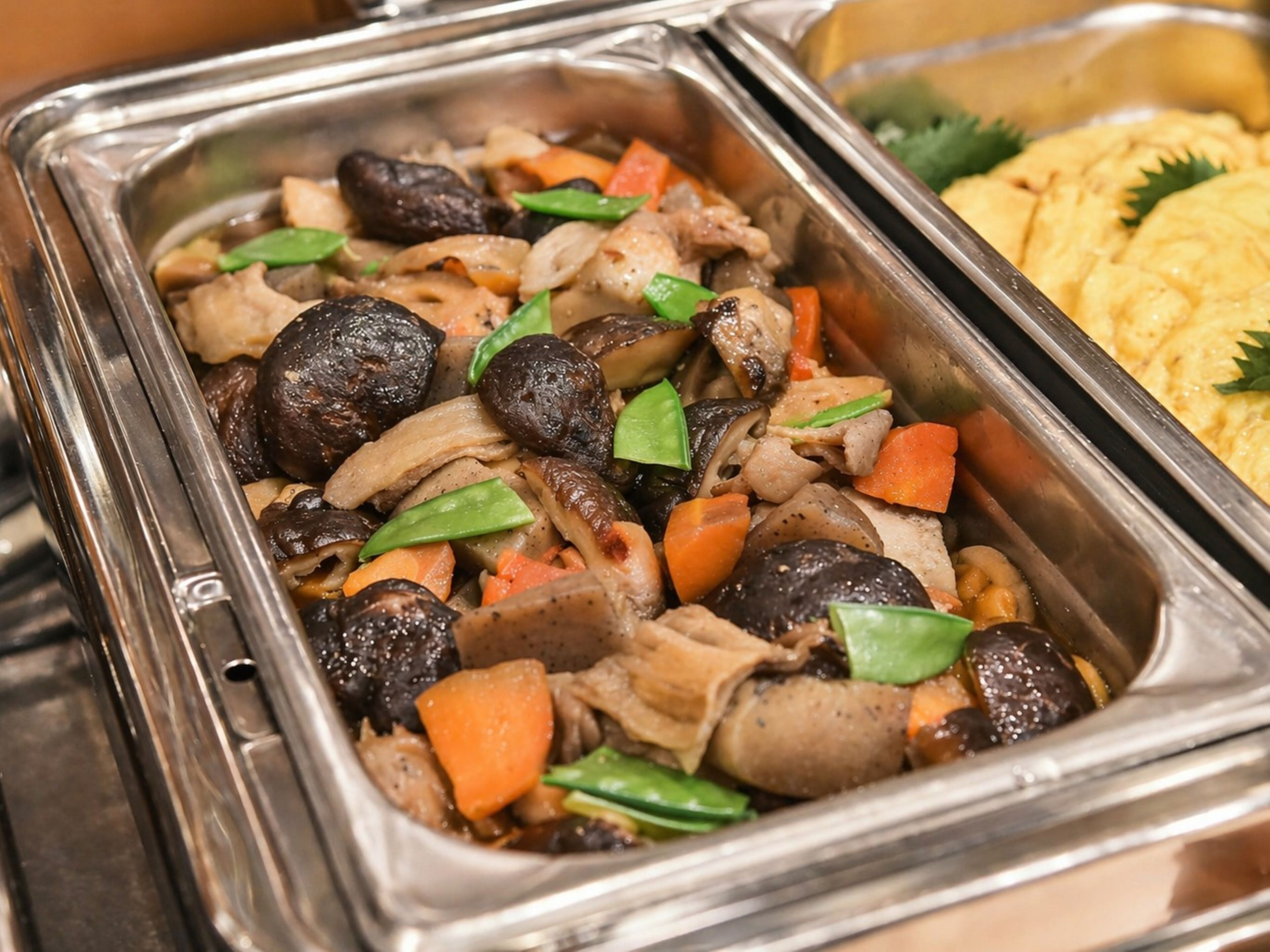 Un bufé con diversos platos, incluyendo carne, verduras y posiblemente comida asiática.