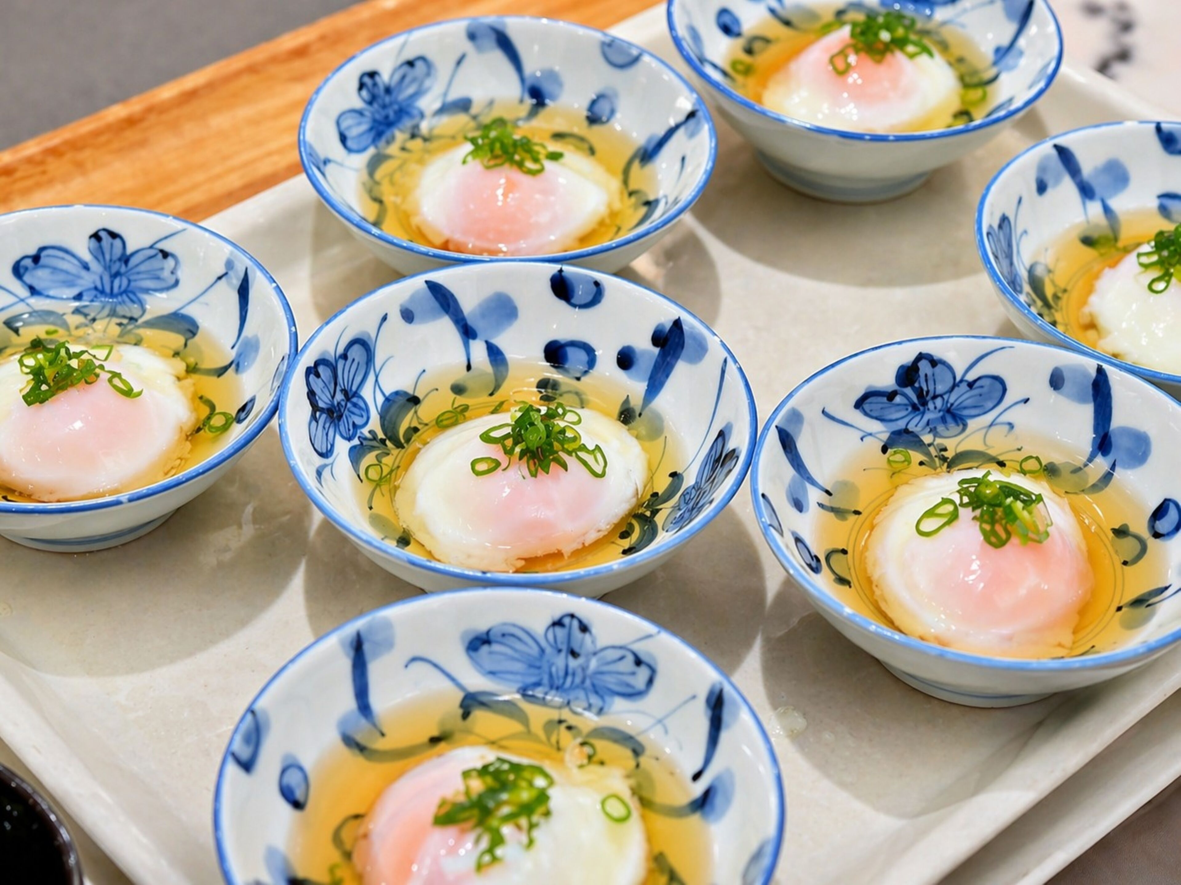 A tray of bowls with a poached egg and green onions.