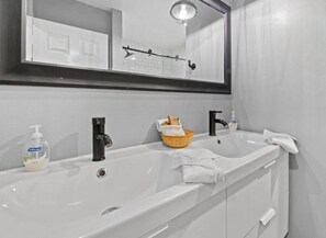 Une salle de bain avec un lavabo blanc, un robinet noir et un miroir au-dessus.