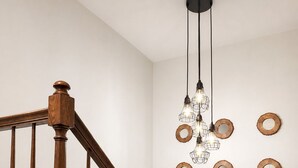 Eine Holztreppe mit einer modernen Leuchte und Wanddekoration.