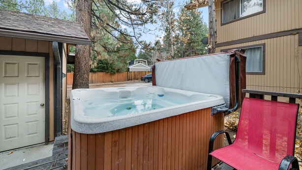 A hot tub with a wooden exterior, a red chair, and a wooden deck. - Bear Retreat - Walk to Snow Summit, Hot Tub, Fireplace (Big Bear Lake)