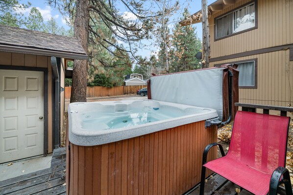 Un bain à remous avec un revêtement extérieur en bois, une chaise rouge et une terrasse en bois.