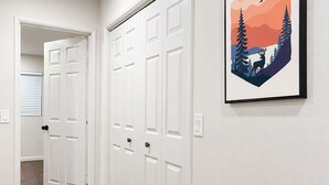 Ein Flur mit weißen Türen, einem gerahmten Bild an der Wand und Holzboden.
