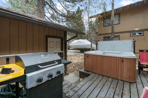 Un barbecue et un jacuzzi sur une terrasse en bois.