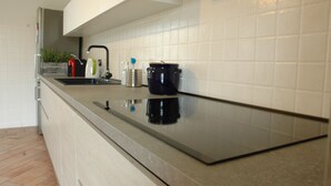 Een moderne keuken met een roestvrijstalen spoelbak, een zwarte waterkoker en een koffiezetapparaat op het aanrecht.