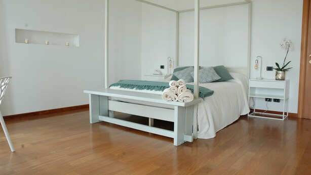 Een moderne slaapkamer met een hemelbed, een nachtkastje en een bijzettafeltje.