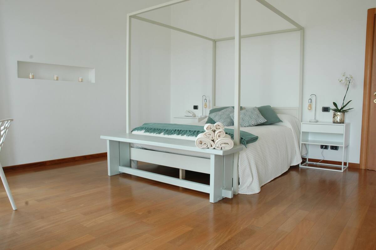 A modern bedroom with a four-poster bed, a bedside table, and a nightstand.
