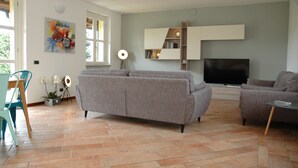 Een moderne woonkamer met een grijze bank, een televisie en een boekenkast.