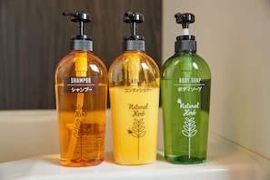 Três frascos de shampoo, condicionador e sabonete natural à base de ervas.