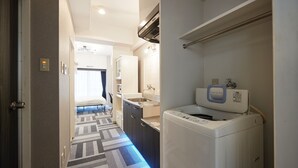 Habitación de hotel con lavadora, kitchenette y baño con toallero.