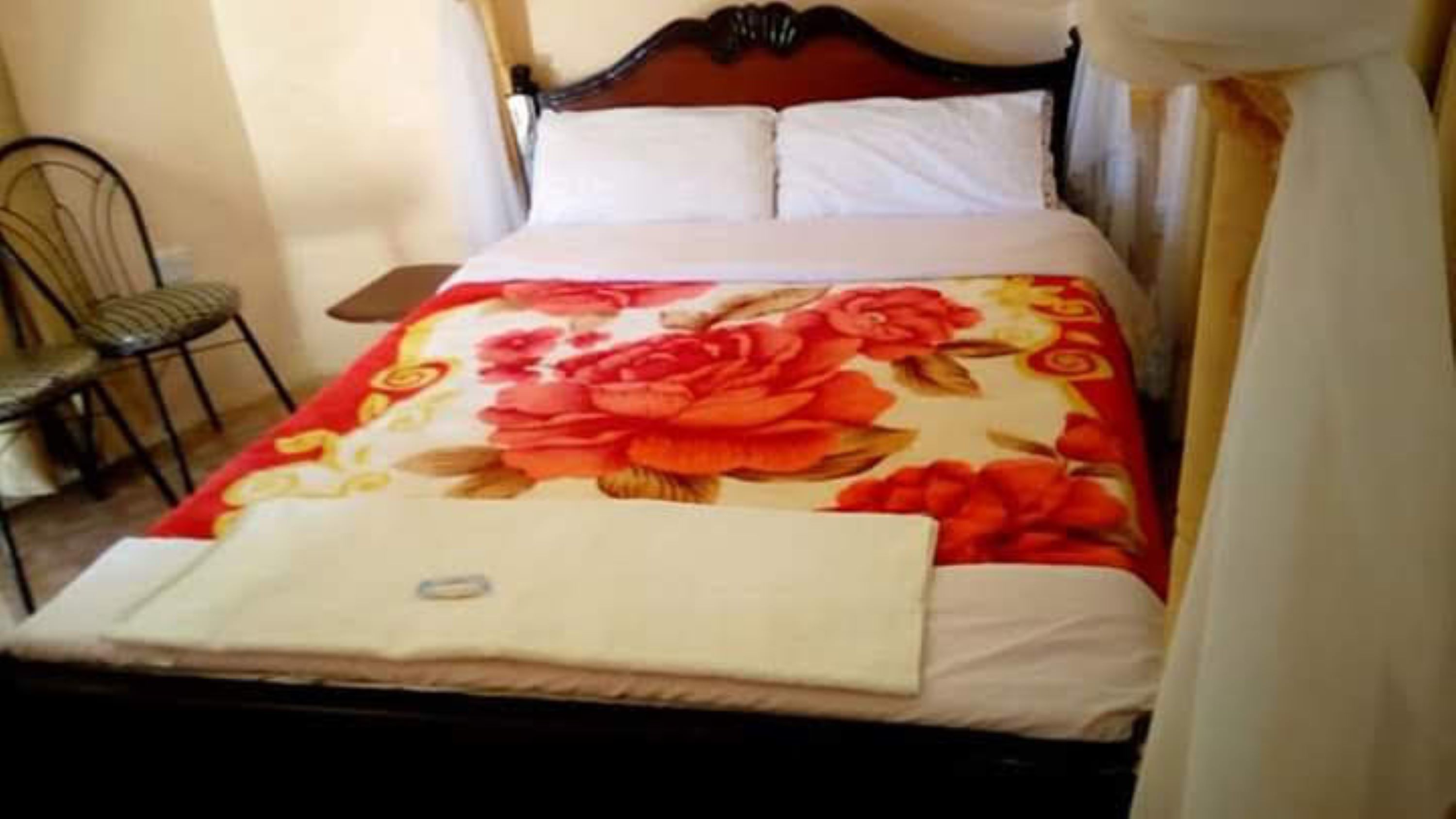 A bed with a floral bedspread, a white pillow, and a wooden headboard.