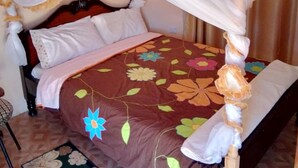 Un lit à baldaquin, une couvre-lit à motifs floraux et un petit tapis.
