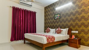 A hotel room with a wooden bed, a nightstand, a red curtain, and patterned wallpaper. - Hilite Inn (Kanayannur)