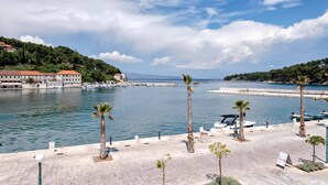 A coastal marina with boats, palm trees, and a clear sky.
