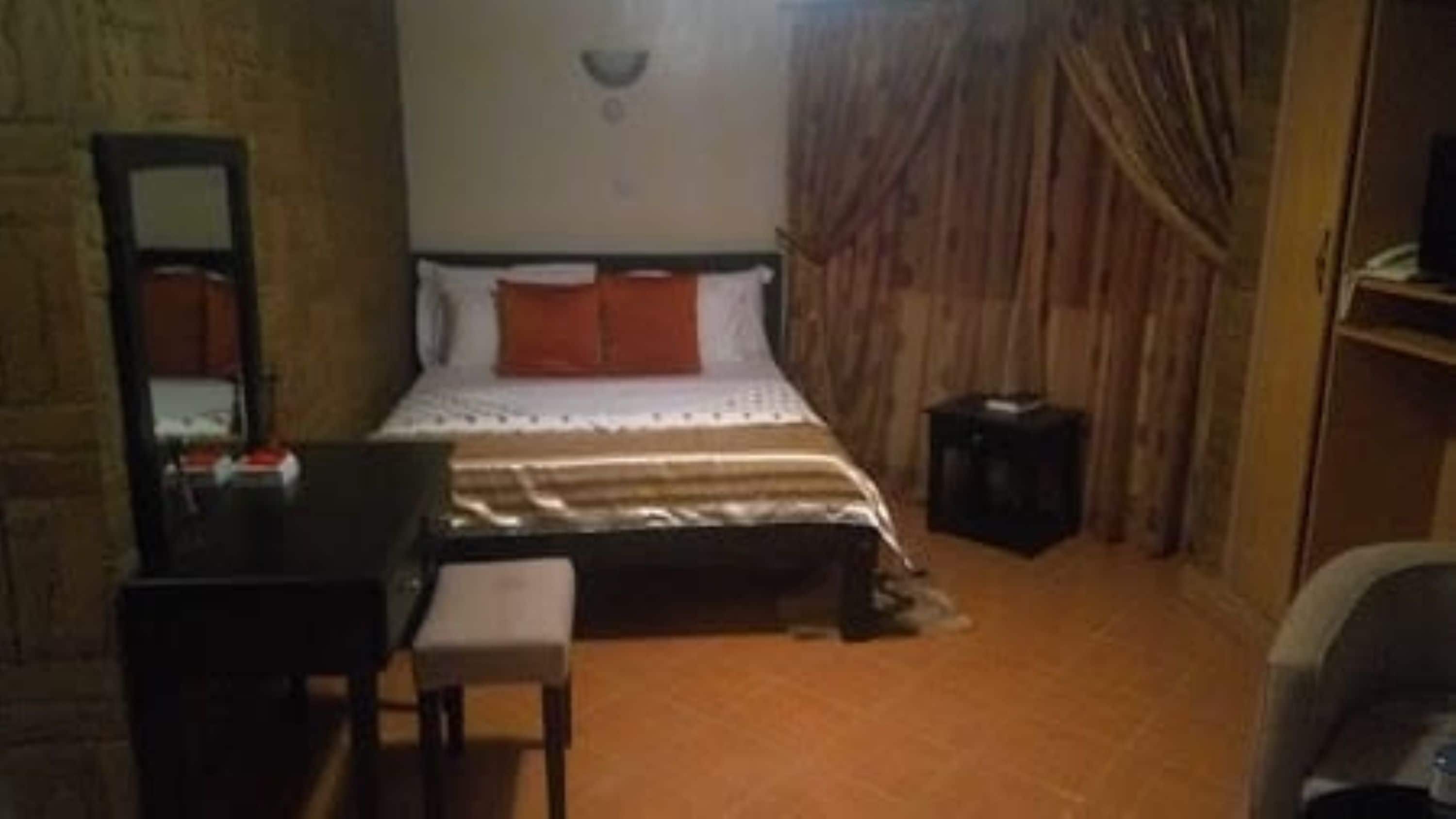 A small, cozy room with a bed, a desk, and a chair.