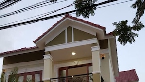 A two-story house with a balcony, a gated entrance, and a stone wall. - Hoi An Lake Shore Homestay (Da Nang)