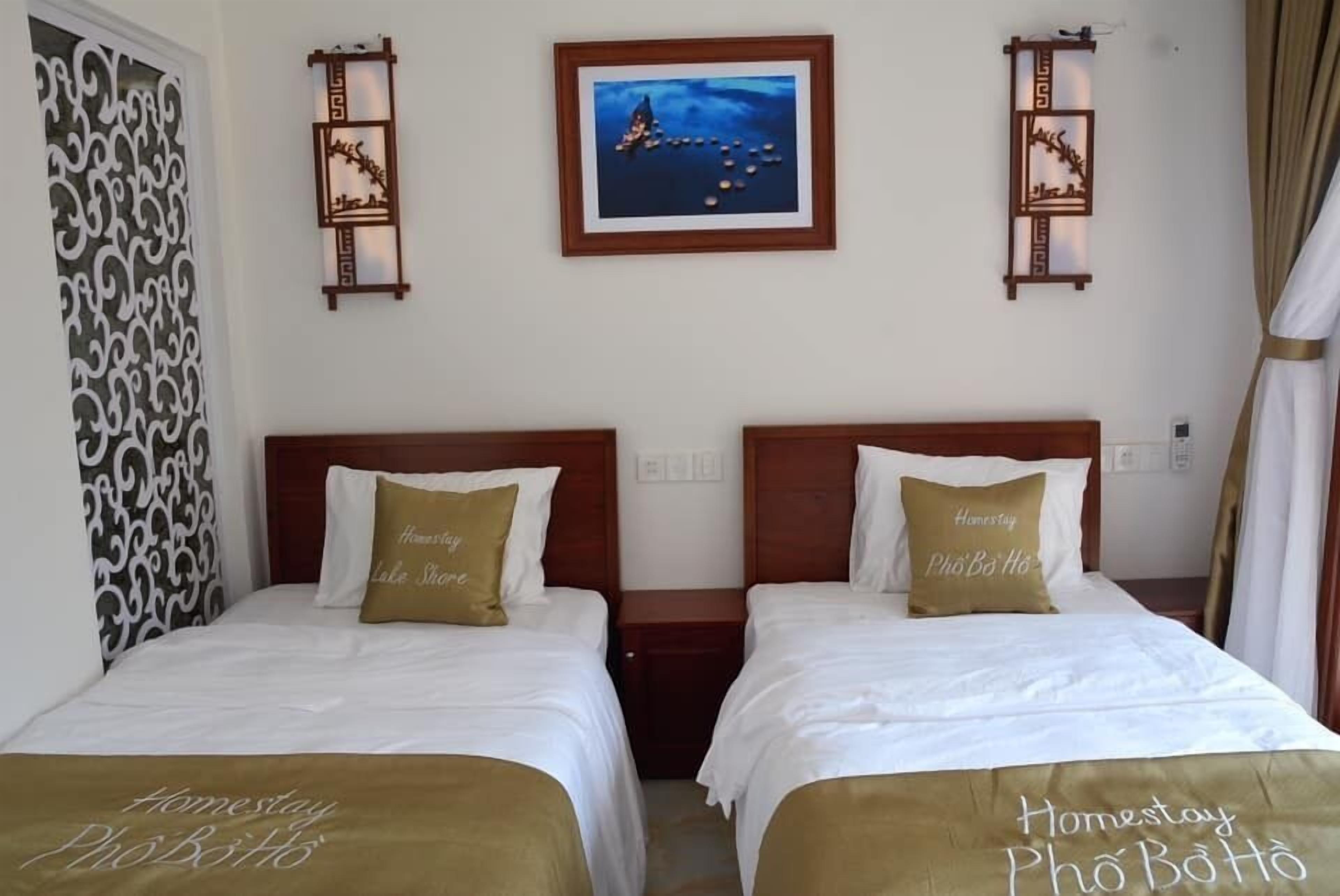 A hotel room with two beds, each with a brown bedspread and pillows, a nightstand, and a framed picture on the wall.