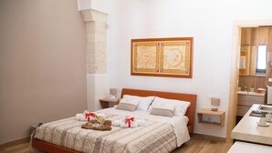 A neatly made bed with a quilted bedspread, a wooden headboard, and two bedside tables with lamps. - La Dimora di Marco (Melendugno)