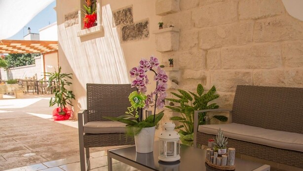 A modern outdoor seating area with a glass-top table, wicker chairs, and a cushioned bench. - La Dimora di Marco (Melendugno)