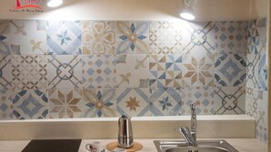A kitchen with a tiled backsplash featuring geometric patterns, a stainless steel sink, and a coffee maker. - La Dimora di Marco (Melendugno)