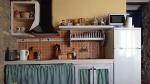 Eine Küche mit einem weißen Kühlschrank, einer Mikrowelle sowie verschiedenen Küchengeräten und -utensilien.